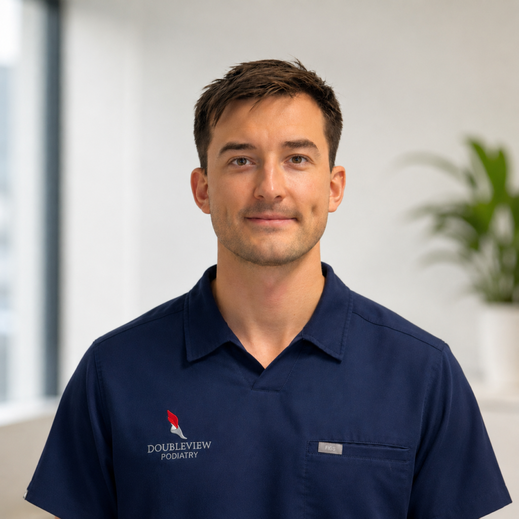 Headshot of Lewis Viney, Clinic Director and Principal Podiatrist at Doubleview Podiatry, wearing a blue clinic uniform